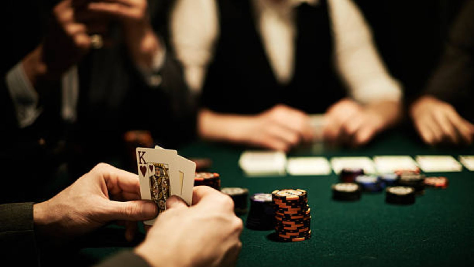 Image of a man confidently holding two kings in his hands while playing poker